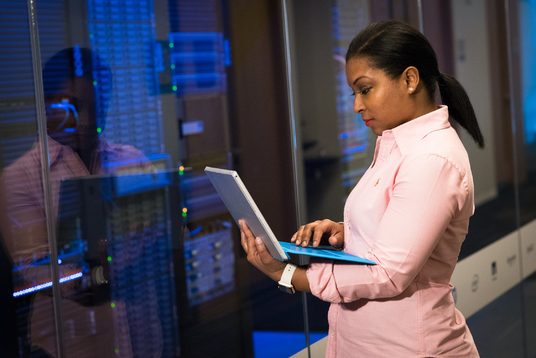 Lady working on a laptop in front of servers.